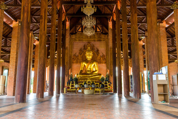 The background of the Wat Pa Kham Charoen is a beautiful old church with a Buddhist statue and a tree-lined temple, with tourists and travelers always making merit in Udon Thani, Thailand.