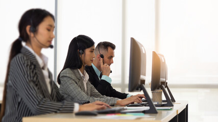 Selective focus on Caucasian man with headset on working in Call Center or Customer Service with colleague