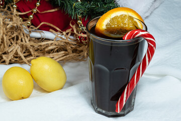 Close-up of a drink. A glass of warming drink with orange and caramel canes. Against the background of a pair of lemons.