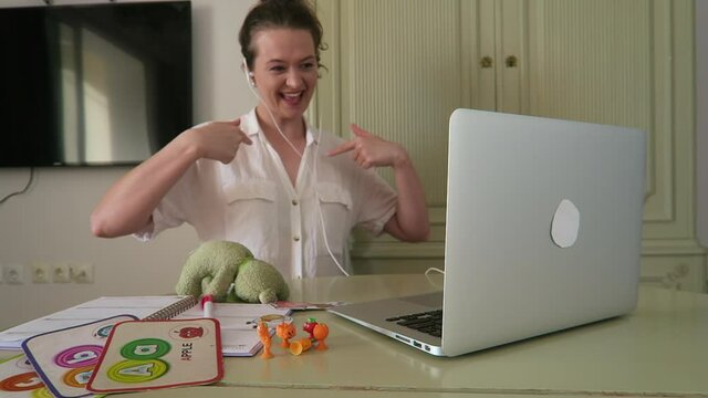 Young, attractive woman teaching English online to children. Teddy bear, enthusiasm, education.