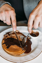 Man eating delicious vegan pancakes with chocolate topping. 