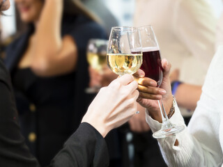 Selective focus on wine glasses were toasted. Businessman and business woman or friends toasting to cheers for Christmas, New Year or happiness party.