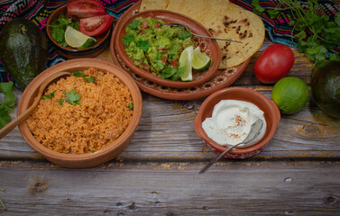 Traditional mexican rice, guacamole, corn tortillas on wooden background