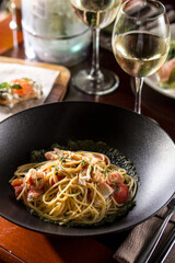 crab meat tomato pasta spaghetti with glass of white wine on the table at restaurant