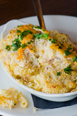 Potatoes au gratin. Potatoes baked in butter, cheese cream sauce, garnished with scallions, parsley and served in cast iron skillet. Classic American restaurant or French bistro side dish.