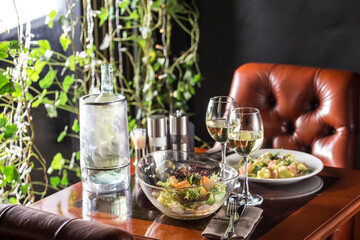 Fresh green salad with spinach, arugula, romaine and carrot in glass bowl on the table at restaurant