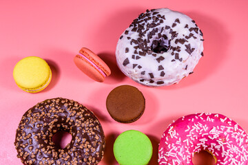 Fresh glazed donuts and french macaroons isolated on a pink background