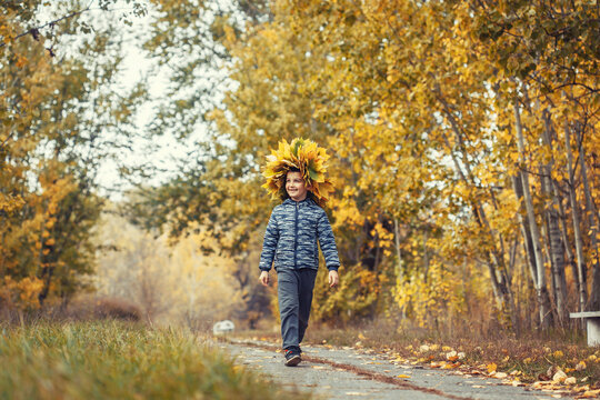 happy kid in the autumn forest wearing a wreath of yellow leaves