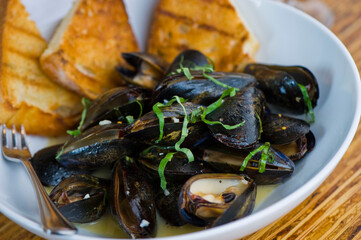 Mussels. Steamed mussels simmered with butter, garlic, shallots, red wine, tarragon, salt and pepper and served with toasted baguettes. Classic French bistro appetizer.