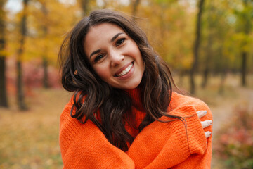 Beautiful brunette happy woman smiling while strolling in autumn forest