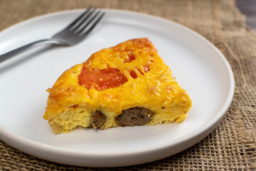 slice of home made crustless sausage quiche with tomato 
