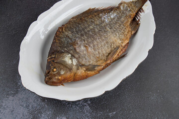 Close-up of fried fish on a white platter . Light background, Copy space