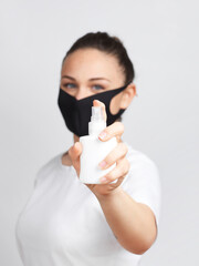 Young woman with mask holding a sanitizer spray