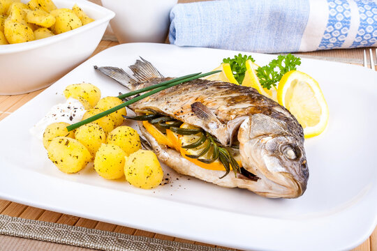 Grilled fish with potatoes, sauce and lemon