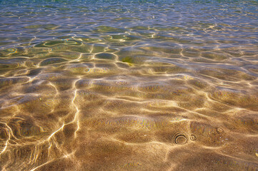 crystal clear sea water in shallow water with sun glare abstract background blur in motion