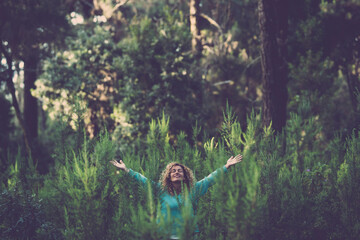 Embracing outdoor and love nature concept with happy beautiful woman in the middle of a forest trees wood in total happiness and joy - earth's day celebration to save the planet