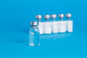 Closeup vaccine bottle on blue isolated background. Lack of coronovirus vaccine.
