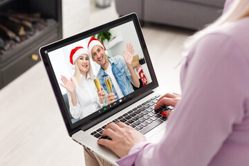 Fototapeta na wymiar Caucasian woman at christmas, having video chat with friends and family using laptop. social distancing during covid 19 pandemic at christmas time.