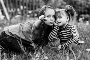 Little sisters are playing outdoors. Black and white photo.