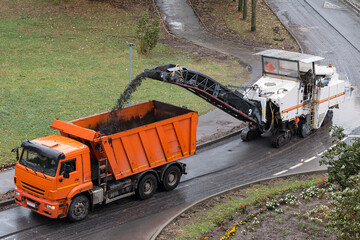 Road milling machine removes old asphalt and loads milled asphalt into the dump truck. Road...