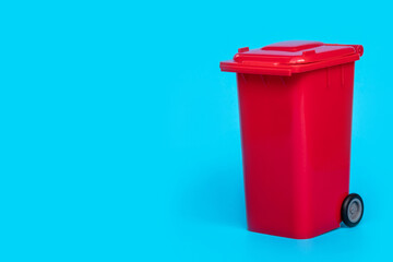 red wheelie waste bin on blue background.