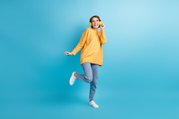 Full length body size photo of pretty girl wearing headphones laughing dancing in casual clothes isolated on vivid blue color background