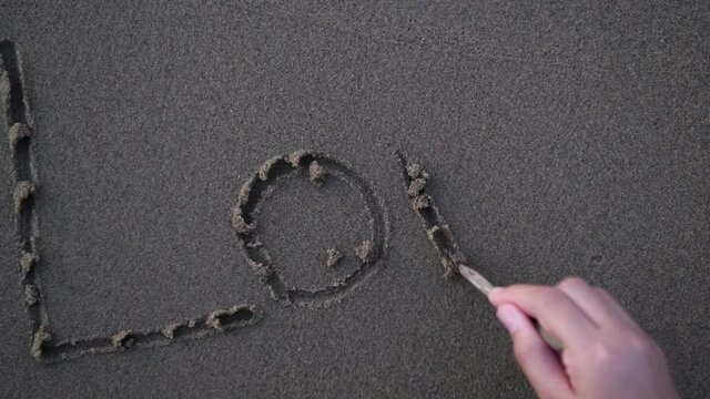 Little hand writing love word on sand, love concept
