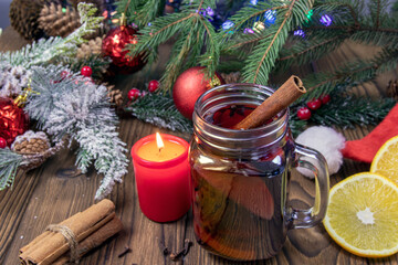 a cup of aromatic hot mulled wine on a wooden table against the background of a Christmas tree with...
