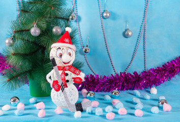 A cheerful but lonely snowman in a red outfit with a hockey stick stands next to a green tree on a blue new year stage