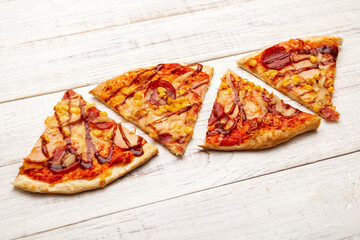 Several slices of pizza on a white wooden background.