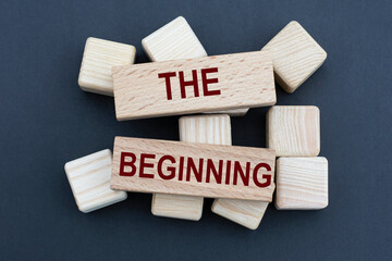 THE BEGINNIN - words on wooden bars on cubes on a gray background