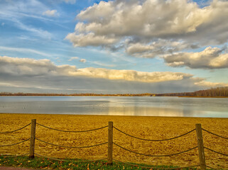 Fototapeta premium Beach at the Pogoria III Lake with sandy beach and clouds reflecting in water.