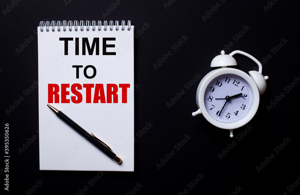 Poster time to restart is written in a white notepad near a white alarm clock on a black background.