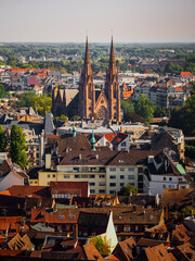 Fototapeta na wymiar Aerial view of the city of Strasbourg. Sunny day. Red tiled roofs. Reformed Church Saint Paul