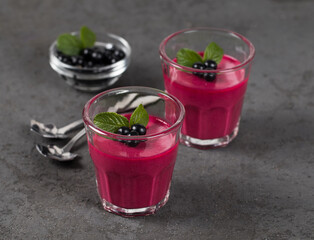 Dessert Panna Cotta cream with black currant in a glass on a dark gray background