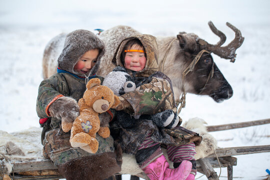 The Yamal Peninsula, the extreme north. Happy boy and girl on reindeer herder pasture in a cold winter day, polar circle, children and animals.