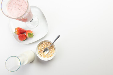  strawberry cereal cocktail for breakfast in a glass cup on a white plate with ingredients. shooting from top to bottom. flat composition. with free space for text, labels and logos