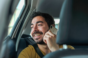 Man using phone in the car and smiling.