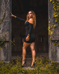 Lifestyle, Caucasian girl with wavy hair in a tight black dress and black high heels. Relaxed an abandoned place full of nature staring with a seductive gaze