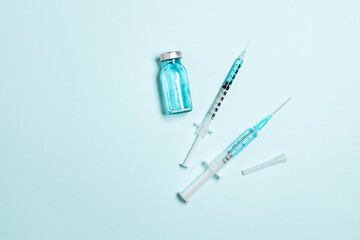 Vaccine vial, glass ampoules and a syringe with medicine on blue background. Minimal horizontal banner. Gdobal vaccination, adults and children