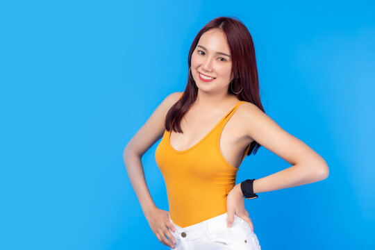 Portrait young asian woman with smile face over blue background copy space. Pretty girl has perfect body. She get dieting. Lovely female wear tank top and arm akimbo. She has long hair. Slender girl