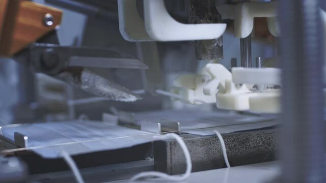 Production of medical protective face masks for air filtration. Coronavirus protection machine, covid-19. Press presses the fixing thread for ear loops or ties. Macro production line, conveyor.