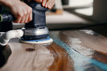 Man polish a wood. Worker with polishing machine.