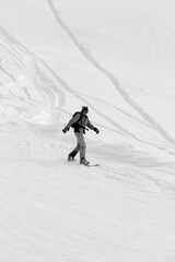 Snowboarder downhill on snowy off-piste slope after snowfall