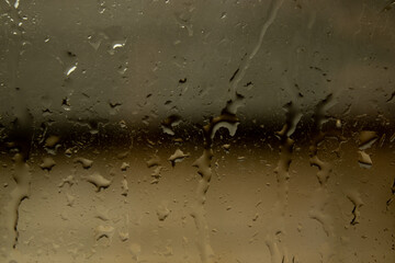 View of glass with water drops and a vintage building behind, close up view. Cold and warm colors. Fall.