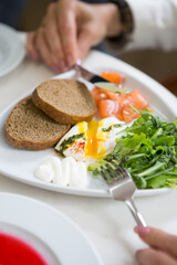 Woman eating poached egg for breakfast