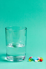 Colored pharmaceutical pills, vitamins and a glass of water.