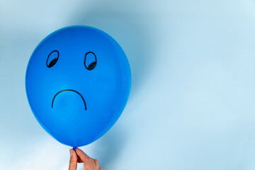 A sad Blue Monday emoticon is drawn on a hot air balloon on a blue background.