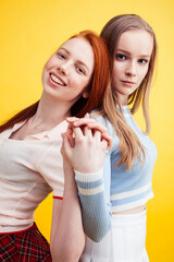 lifestyle people concept: two pretty young school teenage girls having fun happy smiling on yellow background