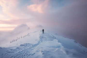 Man mountaineer walking with footprint on snowy mountain and colorful sky in blizzard at sunrise